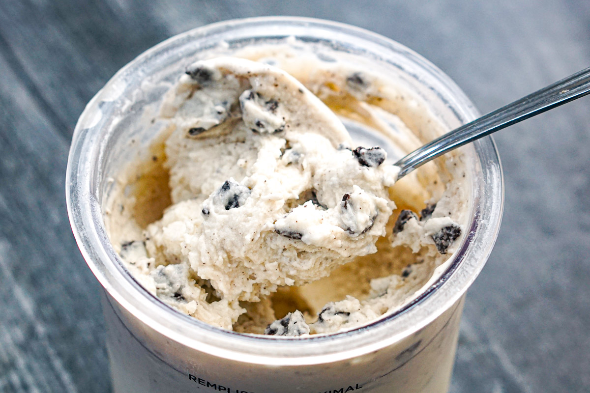 Closeup of a pint of Ninja Creami cookies and cream ice cream with a spoon.