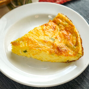 White plate with a piece of the keto crustless cottage cheese quiche.