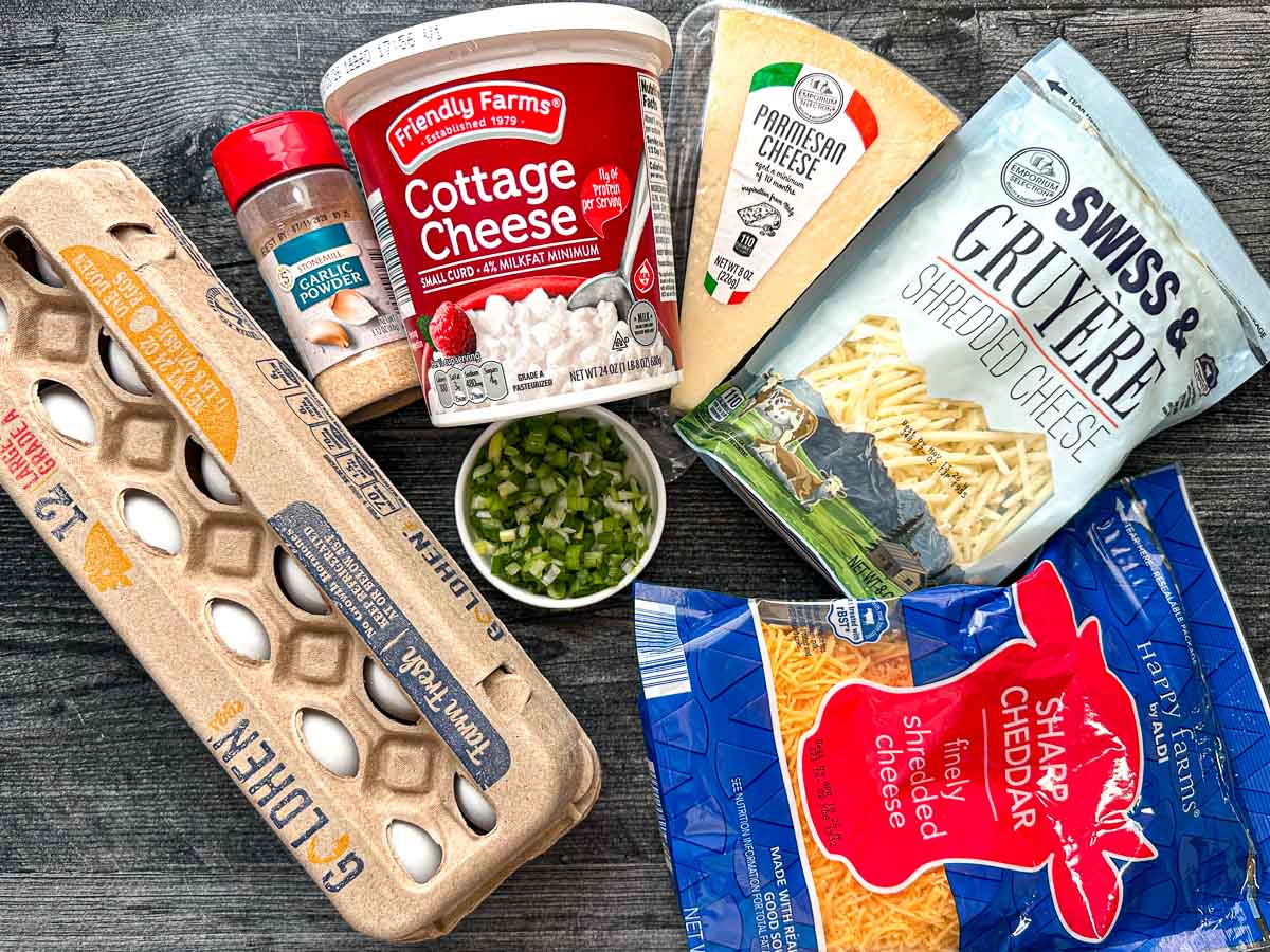 Recipe ingredients - eggs, garlic powder, cottage cheese, green onions, cheddar cheese, parmesan cheese and gruyere cheese.