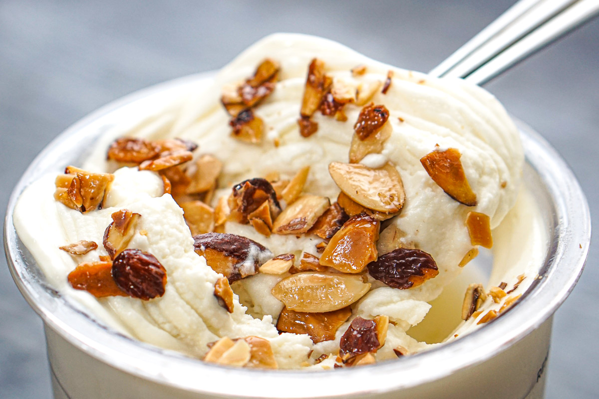 Closeup of the finished pint of low carb high protein toasted almond ice cream with toasted nuts on top.