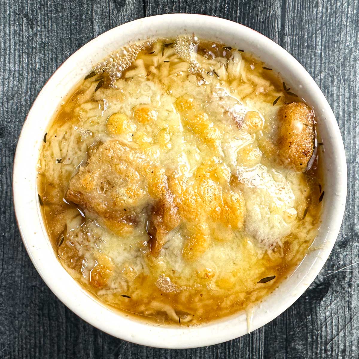 Aerial view of a white bowl of keto French onion soup.
