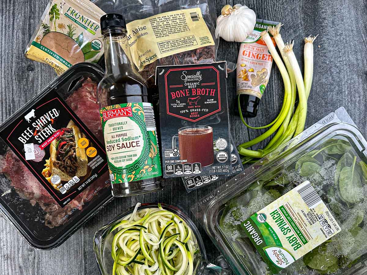 Recipe ingredients are shaved beef, star anis, 5 spice, garlic, ginger, green onions, spinach, beef broth, zucchini noodles and soy sauce.