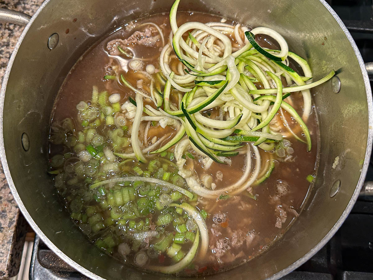 Soup with the zucchini noodle sand green onions added.
