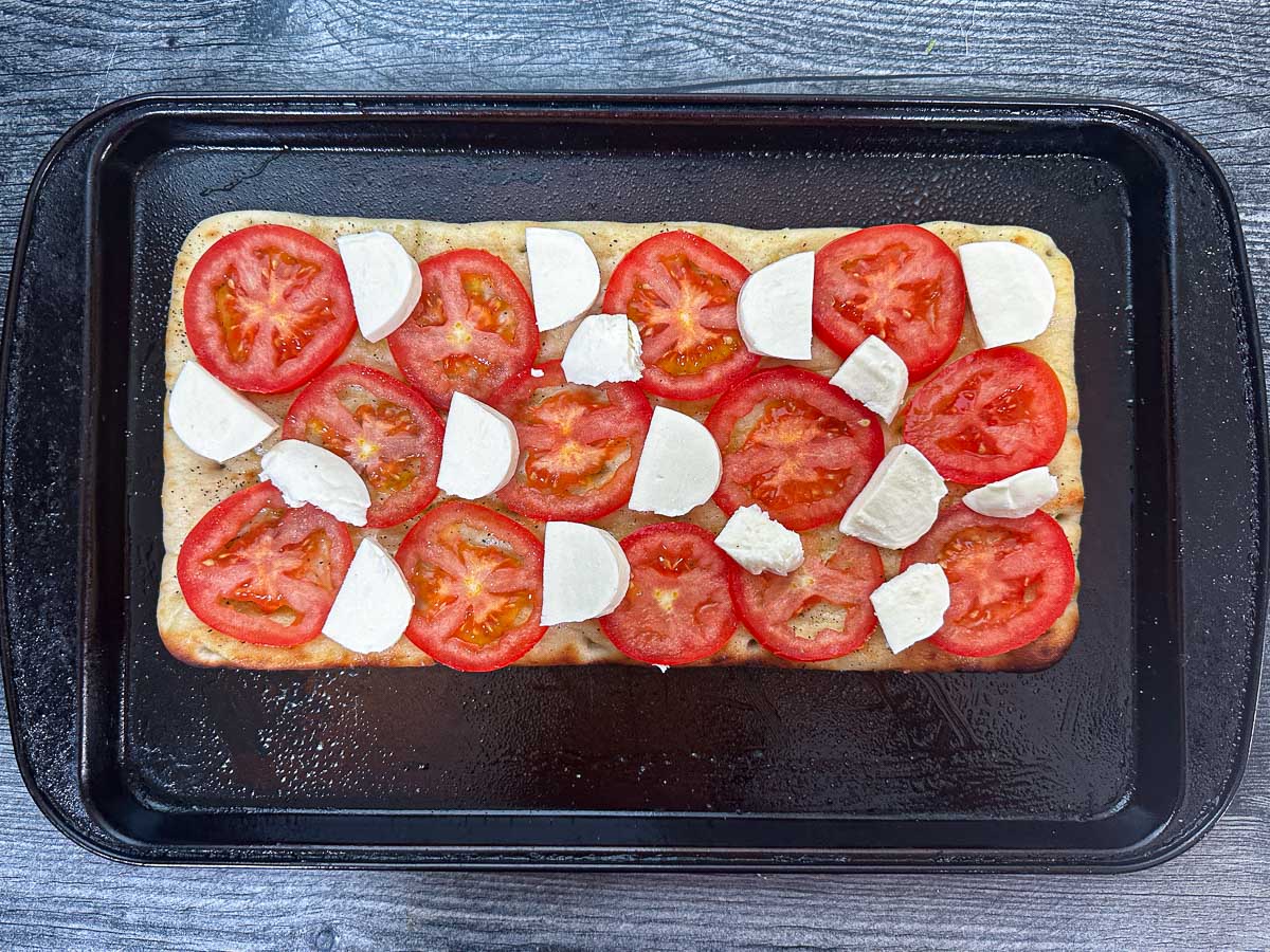 Baking sheet with a crust, tomatoes and cheese.