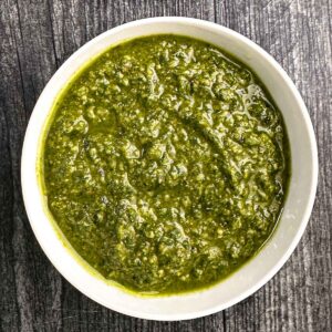 White bowl with basil pesto with walnuts.