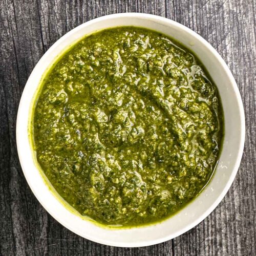 White bowl with basil pesto with walnuts.