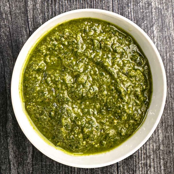 White bowl with basil pesto with walnuts.