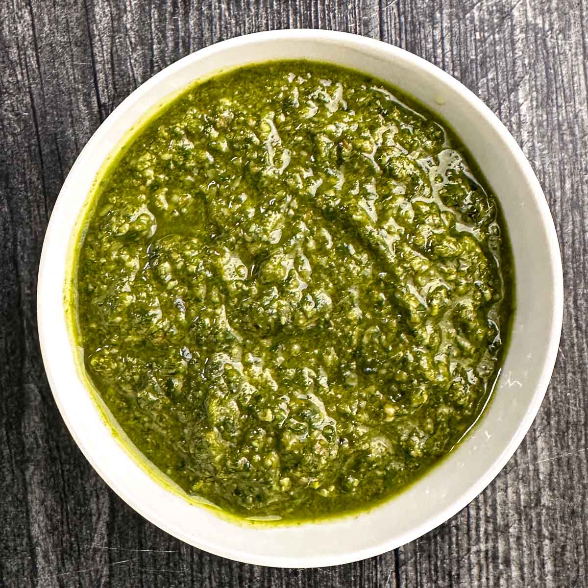 White bowl with basil pesto with walnuts.