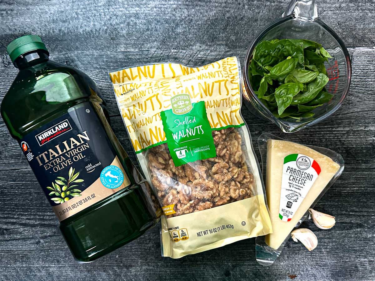 Recipe ingredients - fresh basil, olive oil, walnuts, parmesan and garlic cloves.
